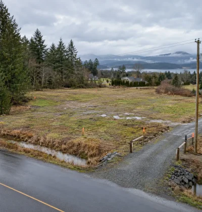 Raw rural land with road access, drainage, utility lines, boundary markers, nearby homes, and water, representing key due diligence checks buyers should verify before purchasing land.
